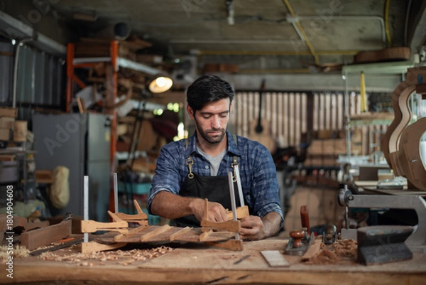 Fototapeta Luthier making guitar using traditional tools in workroom with manual tools