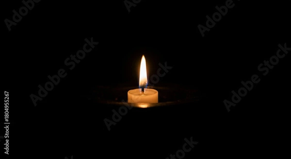 Fototapeta candle flame glowing softly in complete darkness, minimal warm look