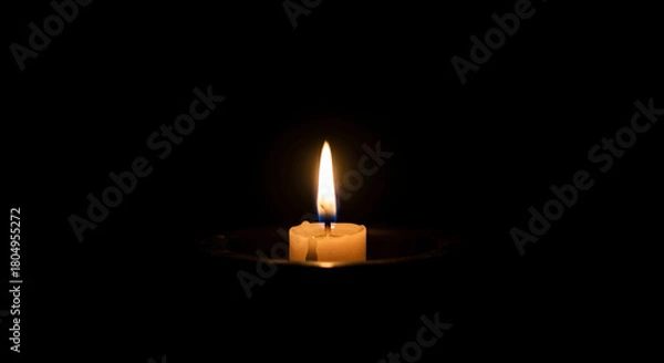 Fototapeta candle flame glowing softly in complete darkness, minimal warm look