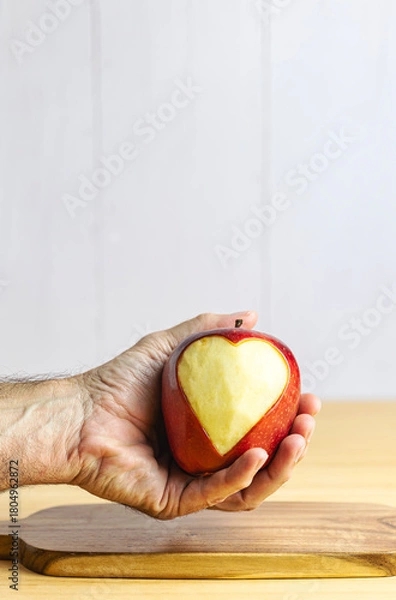 Fototapeta Hand showing an apple with a carved heart