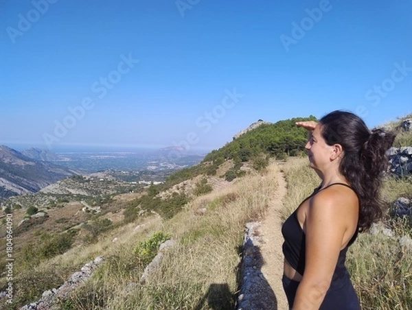 Obraz Woman Enjoying Scenic Mountain View on a Sunny Hiking Trail