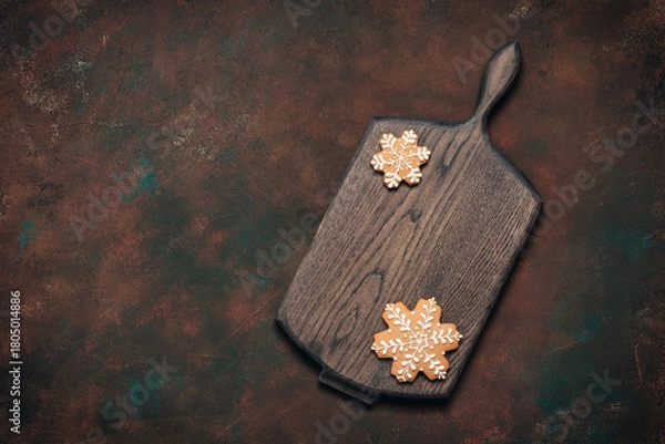 Fototapeta Christmas dark culinary background with wooden board and gingerbread snowflakes, top view, flat lay, copy space;