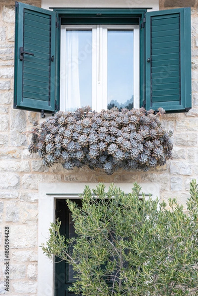 Fototapeta Window Shutter Open With Flower Box Under Terracotta Roof Tiles on Stone Wall