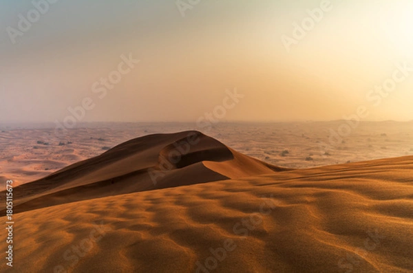 Fototapeta The sun rising on the pristine and untouched red dunes in the desert near Dubai