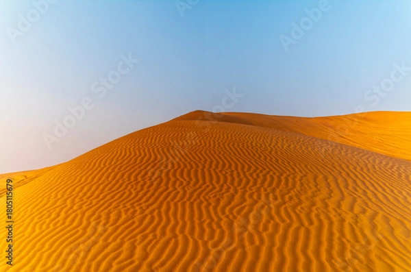 Fototapeta The sun rising on the pristine and untouched red dunes in the desert near Dubai