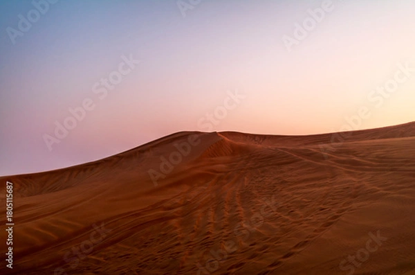 Fototapeta The sun rising on the pristine and untouched red dunes in the desert near Dubai