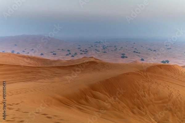 Fototapeta The sun rising on the pristine and untouched red dunes in the desert near Dubai