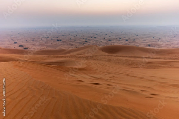 Fototapeta The sun rising on the pristine and untouched red dunes in the desert near Dubai