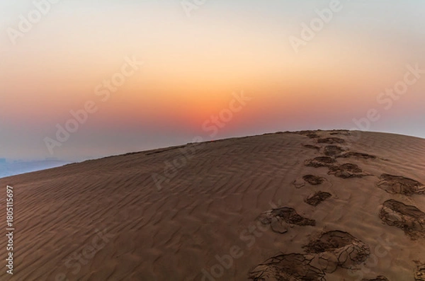 Fototapeta The sun rising on the pristine and untouched red dunes in the desert near Dubai