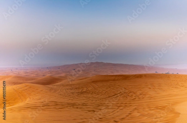 Fototapeta The sun rising on the pristine and untouched red dunes in the desert near Dubai