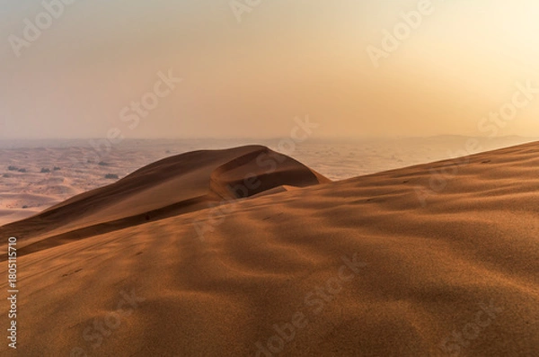 Fototapeta The sun rising on the pristine and untouched red dunes in the desert near Dubai