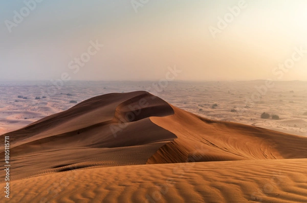 Fototapeta The sun rising on the pristine and untouched red dunes in the desert near Dubai