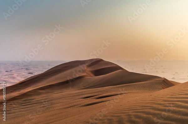 Fototapeta The sun rising on the pristine and untouched red dunes in the desert near Dubai