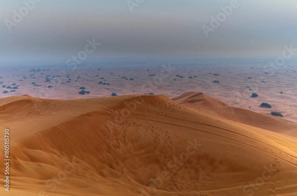 Fototapeta The sun rising on the pristine and untouched red dunes in the desert near Dubai