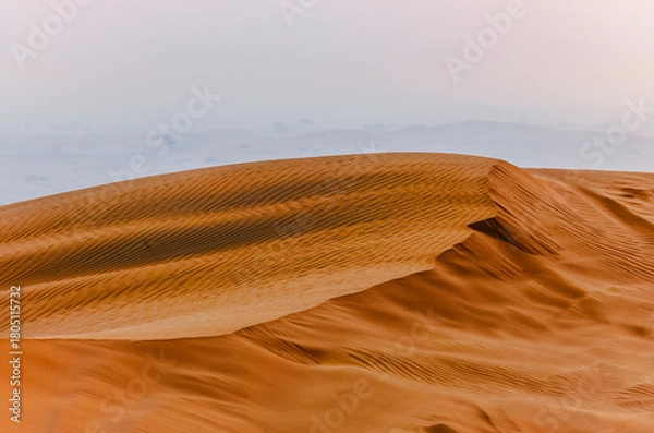 Fototapeta The sun rising on the pristine and untouched red dunes in the desert near Dubai