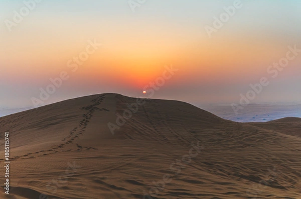 Fototapeta The sun rising on the pristine and untouched red dunes in the desert near Dubai