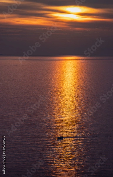 Obraz Sunset over the sea with strong orange reflections, and a boat crossing that reflection. From a viewpoint in Corniglia, Cinque Terre, Italy