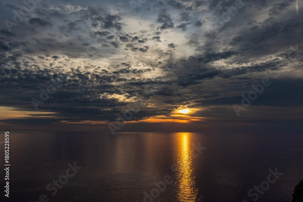 Obraz Sunset over the sea with a strong reflection of the sun on the water and clouds in the sky, from a viewpoint in Corniglia, Cinque Terre, Italy