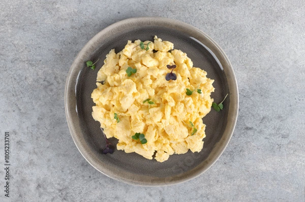 Obraz Scrambled eggs with green onions on a gray plate on a gray background. Healthy breakfast. Top view. 