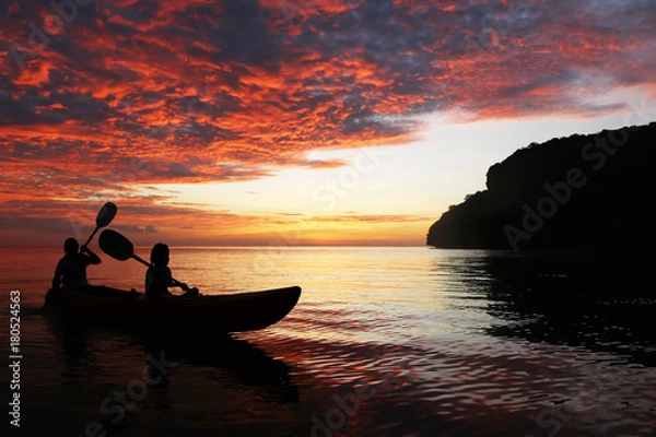 Fototapeta Silhouette mother and daughter kayaking in the ocean around the island
