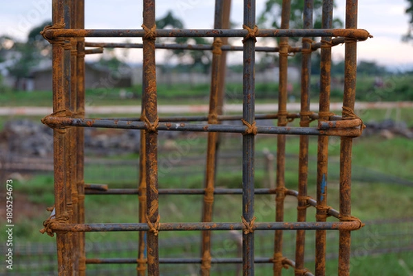 Fototapeta A close-up view of a rust-textured steel rebar frame used for house foundation construction, tightly tied with wire to form a strong structural grid.