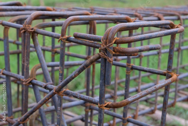 Fototapeta A close-up view of a rust-textured steel rebar frame used for house foundation construction, tightly tied with wire to form a strong structural grid.