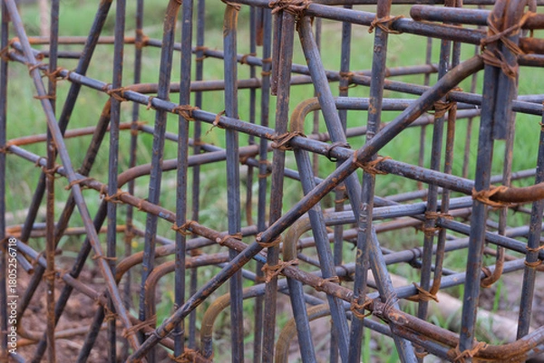 Fototapeta A close-up view of a reinforced concrete footing structure, commonly known as a “cakar ayam” foundation, made of steel rebar arranged in a grid pattern at a residential construction site