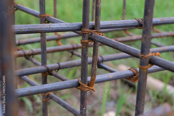 Fototapeta A close-up view of a rust-textured steel rebar frame used for house foundation construction, tightly tied with wire to form a strong structural grid.