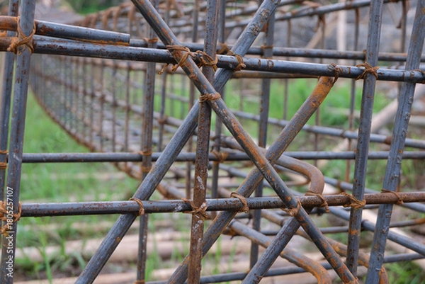 Obraz A close-up view of a rust-textured steel rebar frame used for house foundation construction, tightly tied with wire to form a strong structural grid.