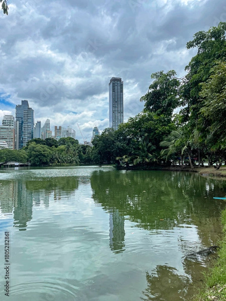 Fototapeta Cloudscape sky on a urban park Lumpini Park in Bangkok, Thailand with skyscrapers in the background