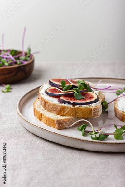 Obraz Slices of white bread with young cream cheese, freshly sliced figs and radish sprouts.