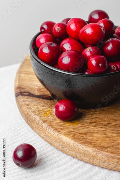 Obraz Close up of shiny cranberries in black bowl on wooden board