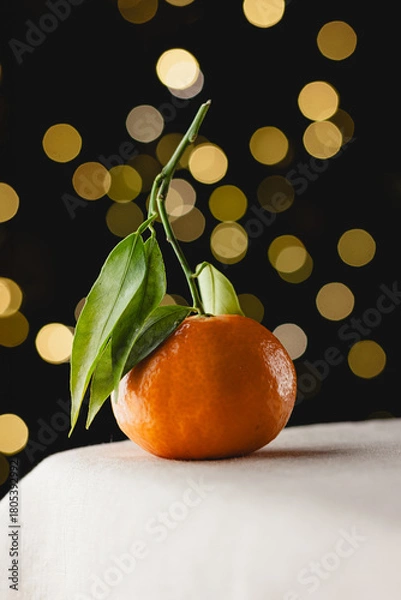 Obraz Fresh tangerine with green leaves and festive bokeh lights