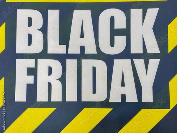 Fototapeta close-up of black friday white bold text on dark background with yellow chevron stripes significant empty space for text banner concept of retail sales, e-commerce, shopping deals