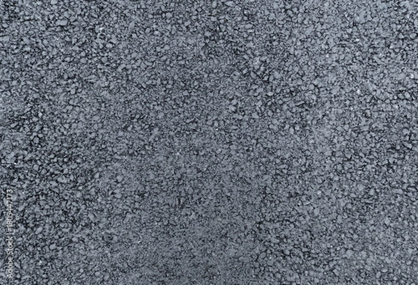 Fototapeta rough texture of a newly laid asphalt surface, filling the entire frame with a dark gray granular composition. The freshly paved road material durable layer.