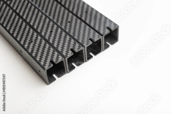 Obraz stack of four identical square-profile carbon fiber beams is diagonally placed on a clean white background.  lightweight composite parts arms for an FPV drone frame.