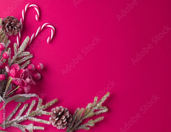 Fototapeta Christmas pink background with poinsettia, decorative fir branch, candy canes and cones for tree decoraton. New Year winter holiday composition with decor and copy space for text, top view.