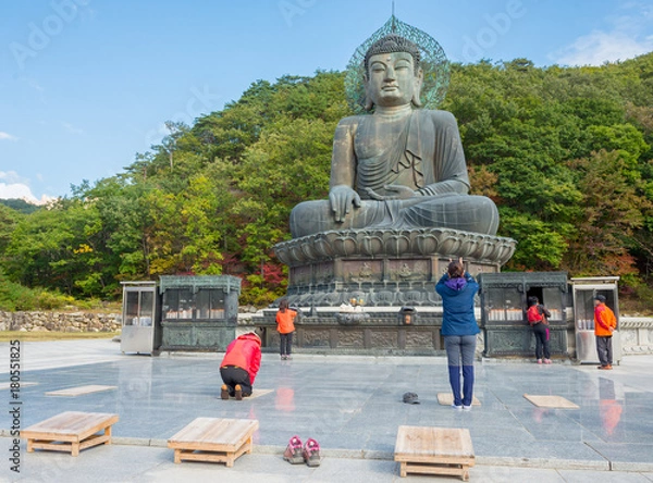 Fototapeta SOKCHO, SOUTH KOREA - October 20, 2013: Prayers at giant statue of Buddha in the Sinheungsa Temple in Seoraksan National Park, South korea