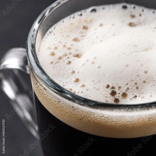 Fototapeta Close Up Of Dark Coffee With Frothy Cream In A Clear Glass Mug On A