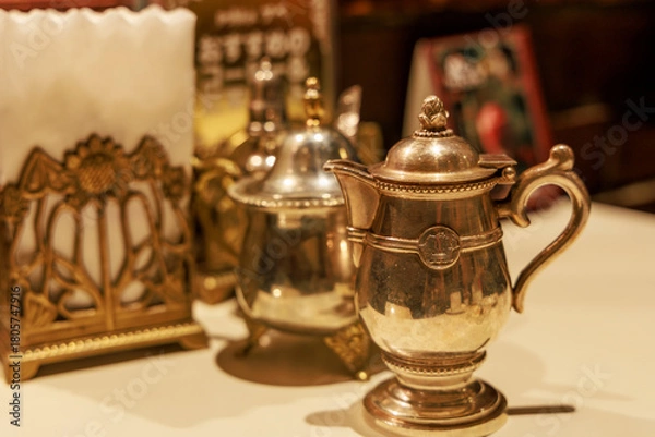 Obraz レトロ喫茶店のテーブルに並ぶアンティーク調のポットとナプキンスタンド

