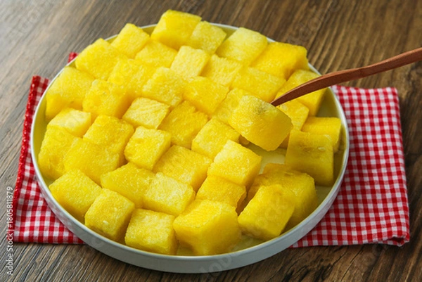 Fototapeta Eating fresh yellow watermelon cubes using a fork. The vibrant yellow color and juicy texture highlight the refreshing and hydrating nature of this tropical fruit.