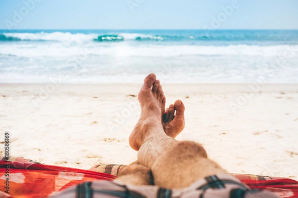 Obraz Mans feet men relaxing on the beach on a deckchair.