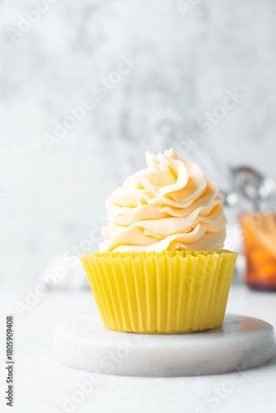 Fototapeta yellow cupcake with orange buttercream frosting on white background, tall buttercream frosting on yellow cupcakes