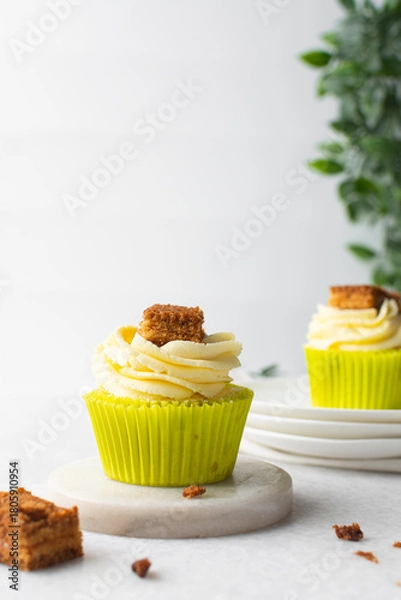 Fototapeta green cupcake with buttercream frosting and a sponge cake garnish on white background, tall buttercream frosting on green cupcakes