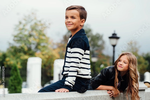 Obraz Two cute kids are sitting on the railing. Marble-stone fountain.