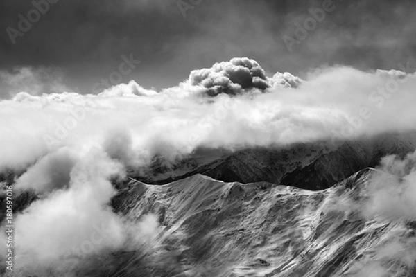 Fototapeta Black and white view on slope for freeriding at mist and sunlight clouds