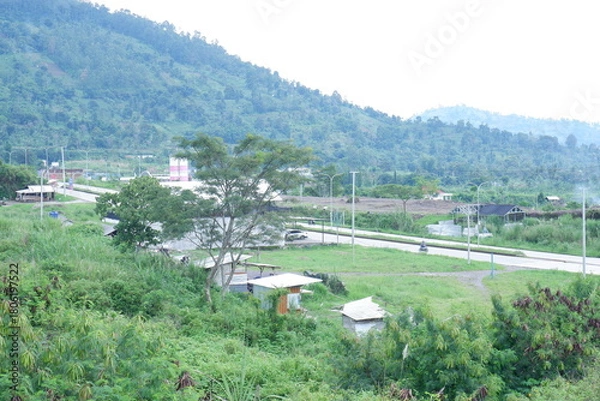 Fototapeta Serene Landscape with Rolling Hills, Lush Greenery, and Rural Roadside Scenery