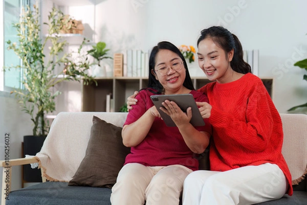 Obraz Digital Togetherness. Two women sharing a tablet experience in a bright living room.