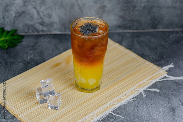 Fototapeta Orange tea is a refreshing blend of black tea and citrusy orange juice, sometimes with jelly cubes and basil seeds for extra texture. This vibrant drink offers a tangy, sweet, and cooling sensation.