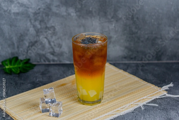 Fototapeta Orange tea is a refreshing blend of black tea and citrusy orange juice, sometimes with jelly cubes and basil seeds for extra texture. This vibrant drink offers a tangy, sweet, and cooling sensation.